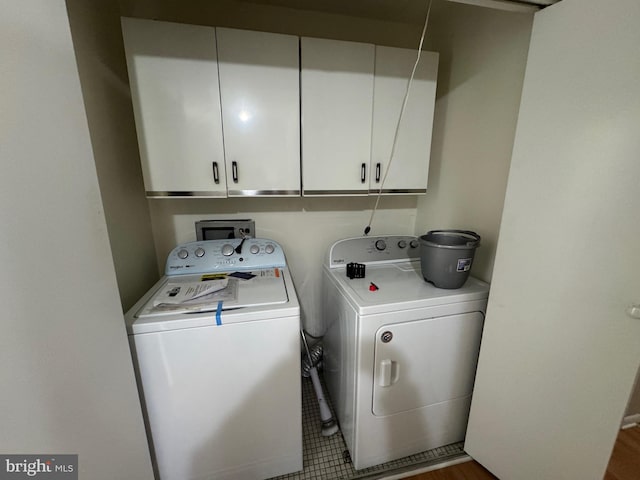 clothes washing area with washer and dryer and cabinets