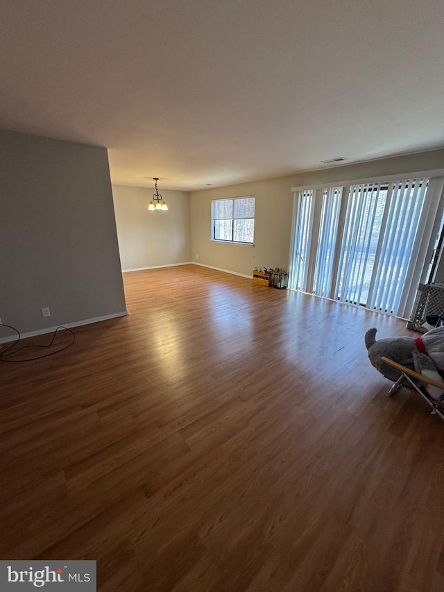 unfurnished living room with hardwood / wood-style floors and a notable chandelier