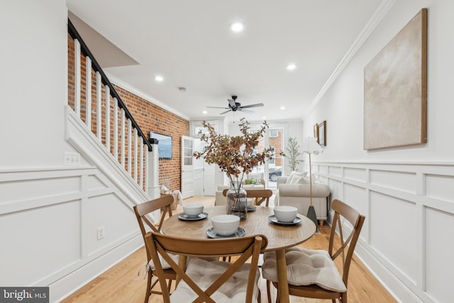 dining area with ceiling fan, light hardwood / wood-style floors, brick wall, and crown molding