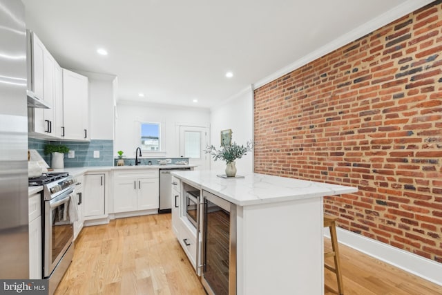 kitchen with brick wall, white cabinets, a kitchen island, stainless steel appliances, and wine cooler