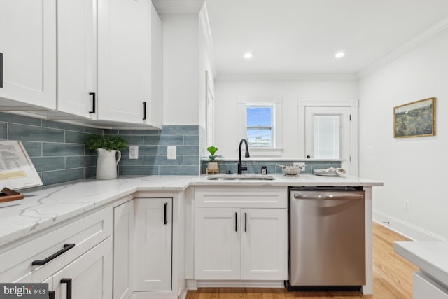 kitchen featuring stainless steel dishwasher, sink, crown molding, and white cabinetry