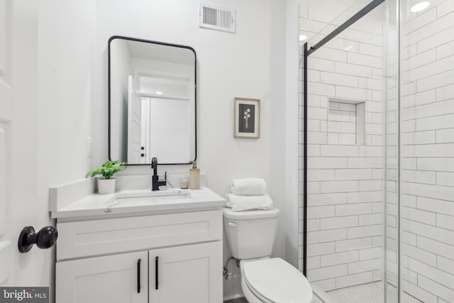 bathroom featuring toilet, a shower with door, and vanity