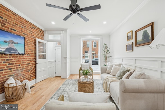 living room featuring ceiling fan, brick wall, crown molding, and light hardwood / wood-style floors