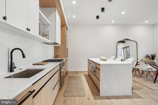 kitchen featuring light hardwood / wood-style floors, decorative backsplash, sink, appliances with stainless steel finishes, and light stone counters