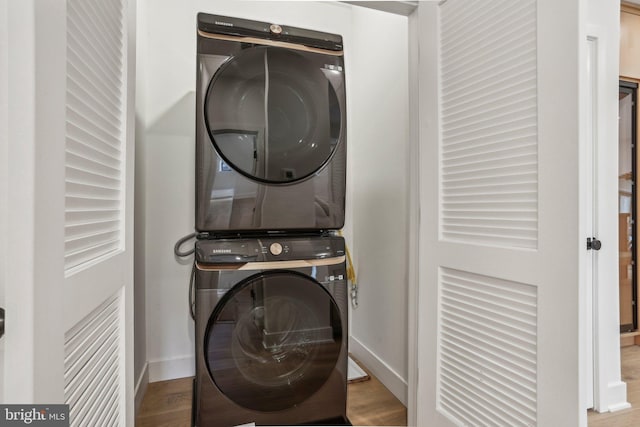 clothes washing area with light wood-type flooring and stacked washer and clothes dryer