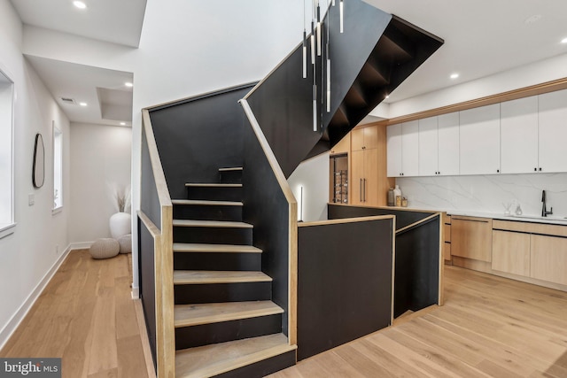 staircase featuring sink and hardwood / wood-style flooring