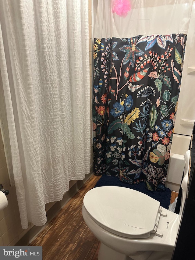 bathroom with hardwood / wood-style floors, toilet, and curtained shower