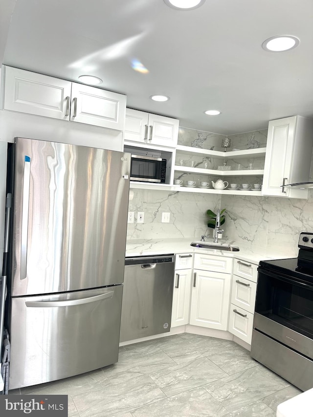 kitchen featuring appliances with stainless steel finishes, white cabinetry, decorative backsplash, and sink