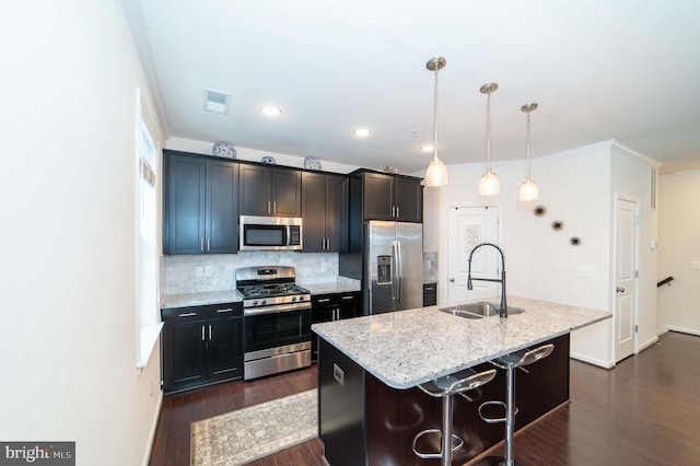 kitchen with sink, stainless steel appliances, a kitchen breakfast bar, a center island with sink, and decorative light fixtures