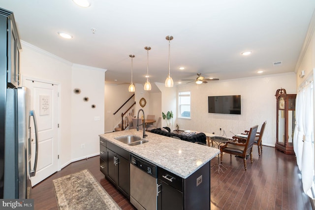 kitchen featuring pendant lighting, sink, stainless steel appliances, dark wood-type flooring, and a center island with sink