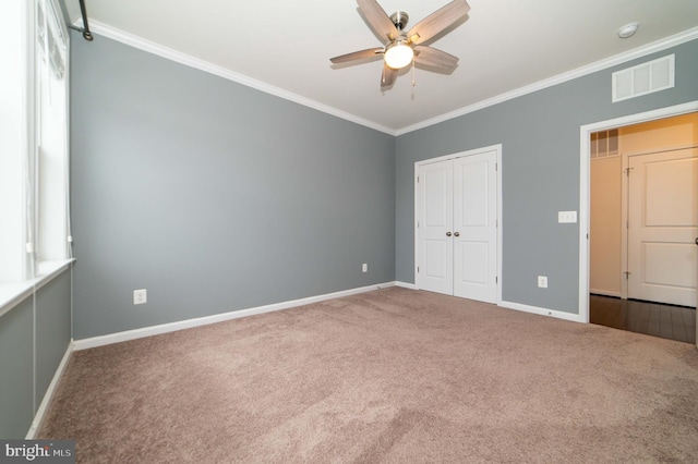 unfurnished bedroom with ornamental molding, a closet, ceiling fan, and carpet flooring