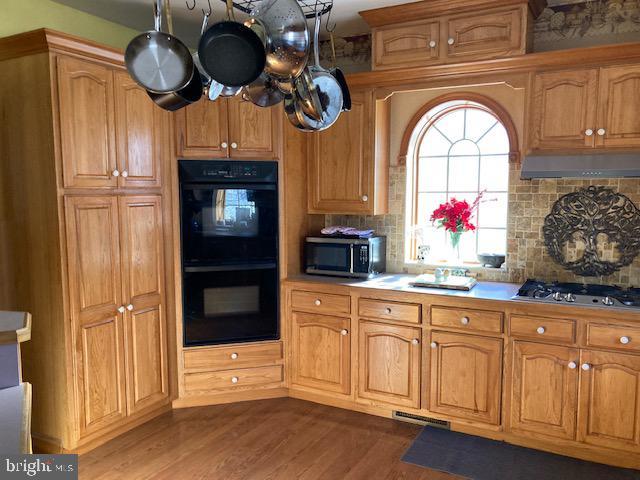 kitchen featuring decorative backsplash, appliances with stainless steel finishes, and dark hardwood / wood-style flooring