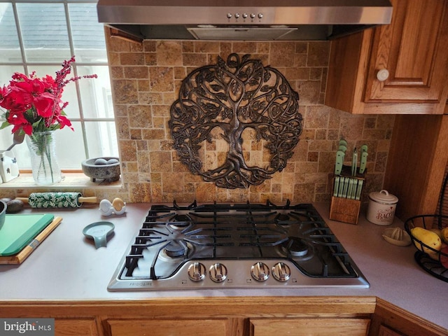 interior details featuring tasteful backsplash, extractor fan, and stainless steel gas cooktop