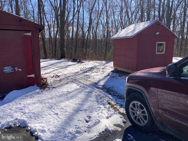 yard layered in snow featuring a storage shed