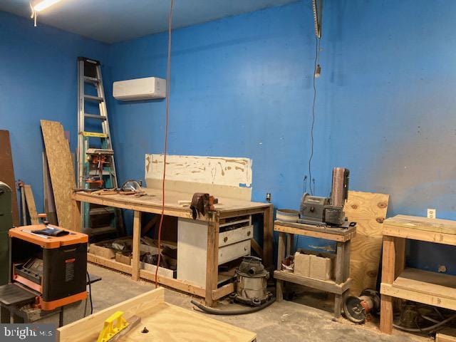 misc room featuring concrete flooring, a workshop area, and a wall unit AC