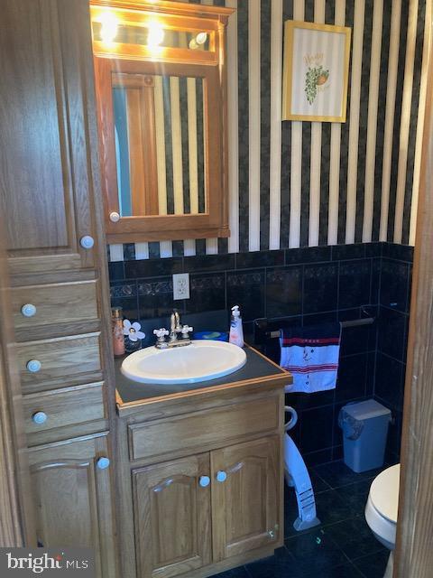 bathroom with tile patterned floors, vanity, toilet, and tasteful backsplash