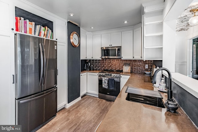 kitchen featuring light hardwood / wood-style floors, decorative backsplash, sink, white cabinetry, and appliances with stainless steel finishes