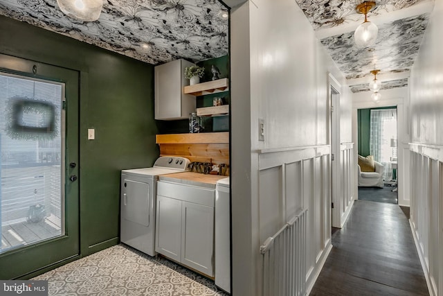 clothes washing area featuring cabinets, light hardwood / wood-style floors, and washer and clothes dryer