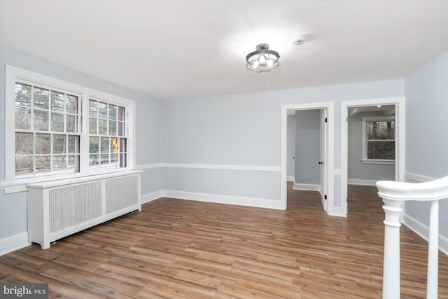 empty room featuring hardwood / wood-style flooring and radiator heating unit