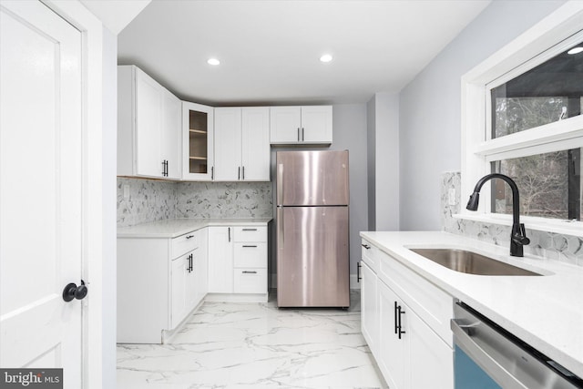 kitchen with white cabinets, decorative backsplash, sink, and stainless steel appliances