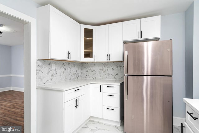 kitchen featuring white cabinetry, stainless steel refrigerator, and tasteful backsplash