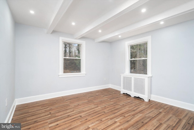 spare room with beam ceiling, wood-type flooring, and radiator heating unit