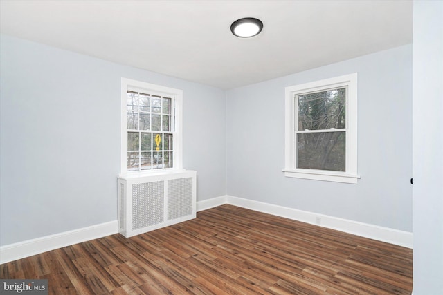 spare room with radiator heating unit and dark wood-type flooring