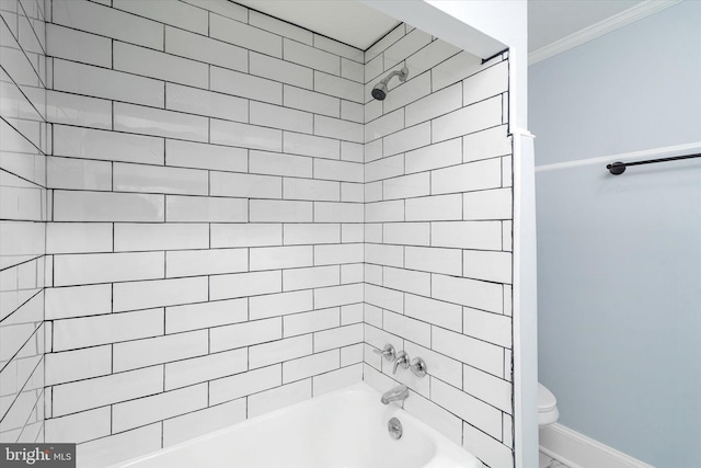 bathroom with toilet, ornamental molding, and tiled shower / bath