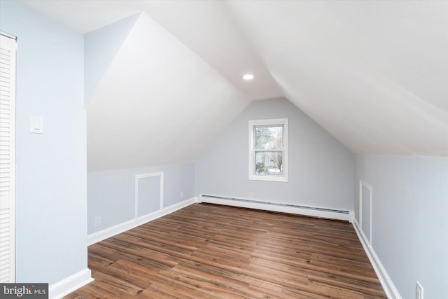 additional living space featuring dark wood-type flooring, lofted ceiling, and a baseboard heating unit