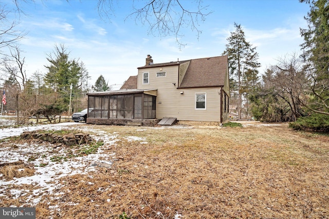 snow covered house with a yard and a sunroom