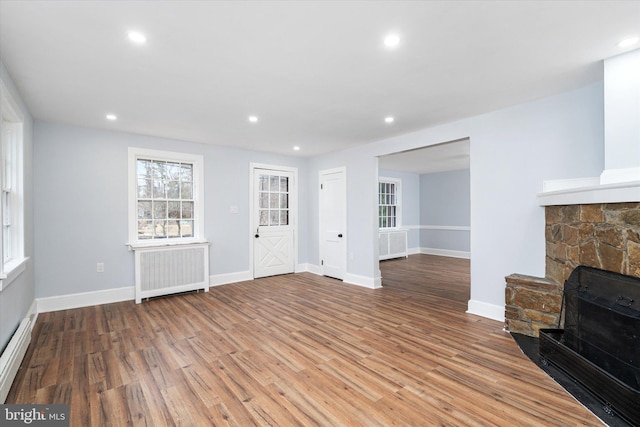 unfurnished living room with a fireplace, hardwood / wood-style floors, and radiator