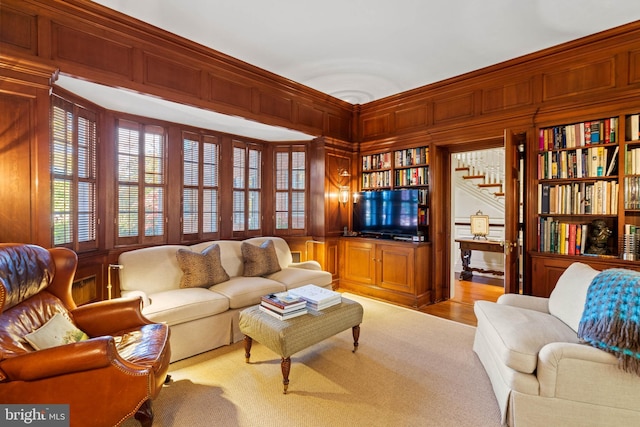 carpeted living room featuring wooden walls and built in features