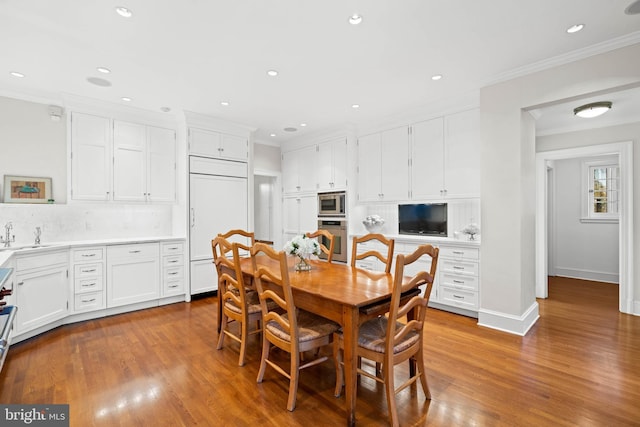 dining space with sink, ornamental molding, and light hardwood / wood-style flooring