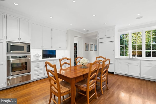 dining room with light wood-type flooring, crown molding, and sink