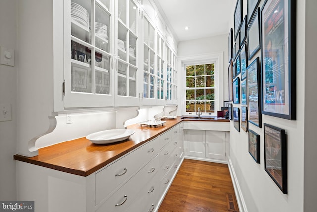 interior space with butcher block counters, dark hardwood / wood-style flooring, and white cabinetry