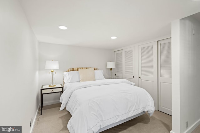 bedroom with two closets and light carpet