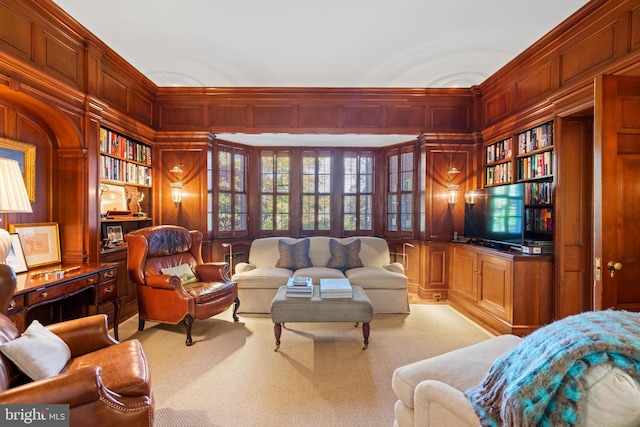 living room with wooden walls, light carpet, and built in shelves