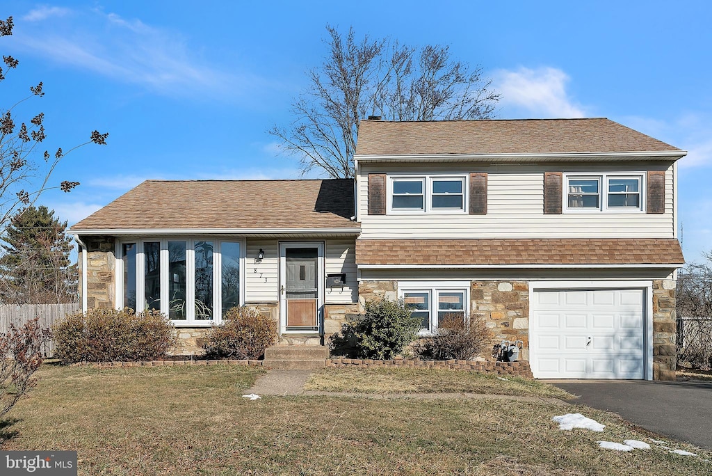 split level home with a garage and a front lawn