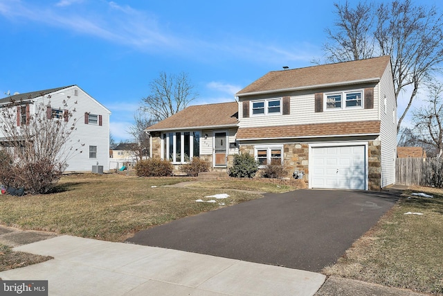 view of front of home with a front lawn, a garage, and central AC unit