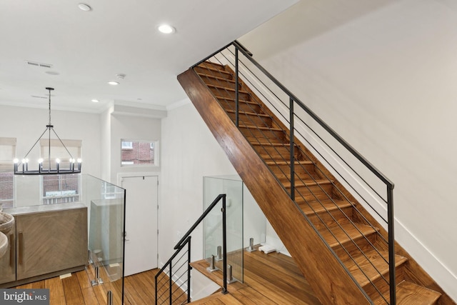 stairway with crown molding, recessed lighting, visible vents, an inviting chandelier, and hardwood / wood-style flooring