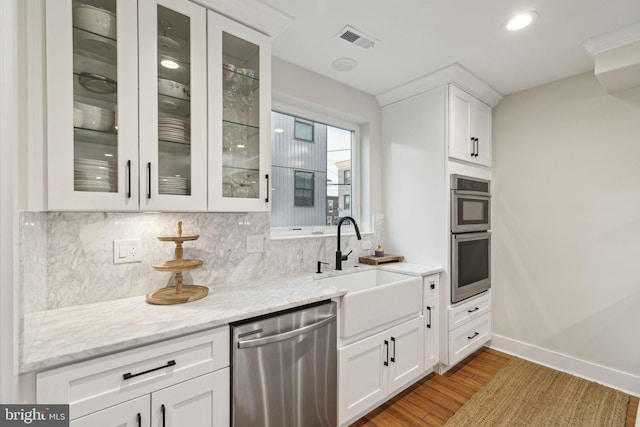 kitchen featuring visible vents, decorative backsplash, appliances with stainless steel finishes, white cabinets, and a sink