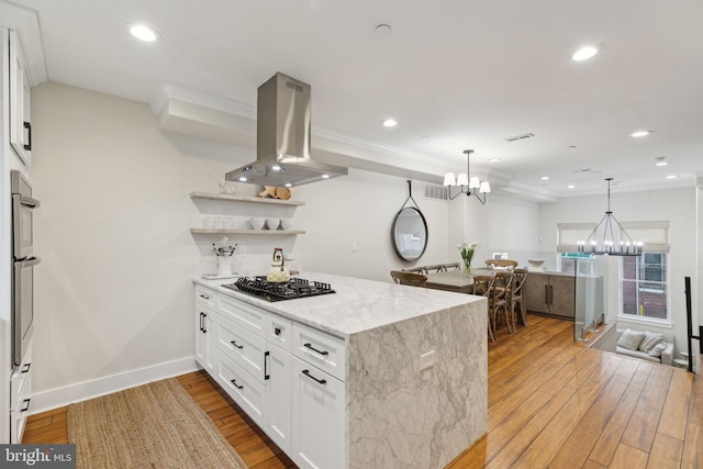 kitchen featuring black gas cooktop, light wood-style flooring, island exhaust hood, and a notable chandelier