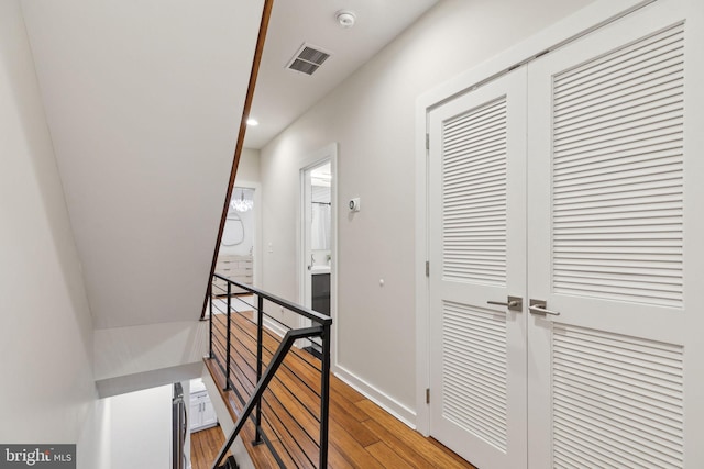 hall with baseboards, visible vents, an upstairs landing, light wood-style floors, and recessed lighting