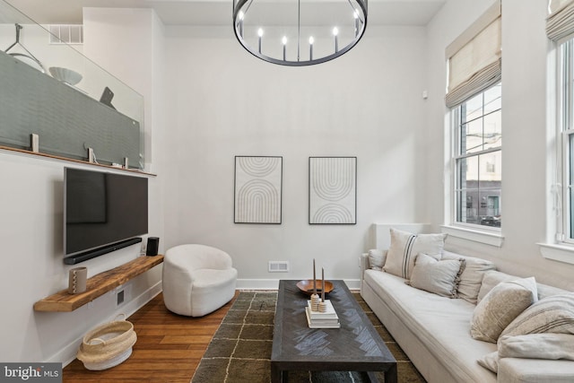 living room featuring an inviting chandelier, wood finished floors, visible vents, and baseboards