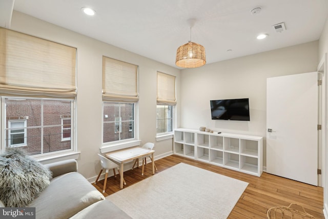 living area with baseboards, visible vents, wood finished floors, and recessed lighting