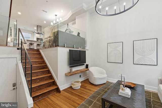 living room with crown molding, recessed lighting, stairway, wood finished floors, and a chandelier