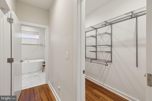 bathroom featuring hardwood / wood-style floors, a soaking tub, and baseboards