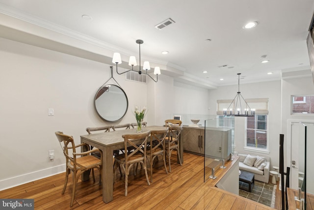 dining area featuring light wood-type flooring, an inviting chandelier, visible vents, and ornamental molding