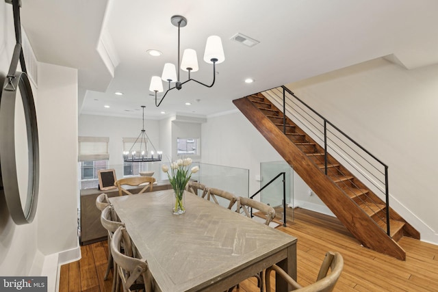 dining room featuring visible vents, a chandelier, hardwood / wood-style floors, and ornamental molding