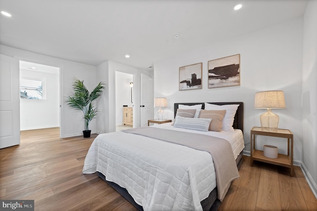 bedroom with connected bathroom and hardwood / wood-style floors